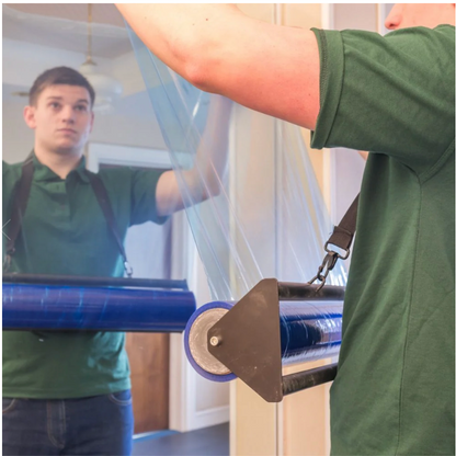 Person in green shirt using a large blue roller to apply plastic sheeting.