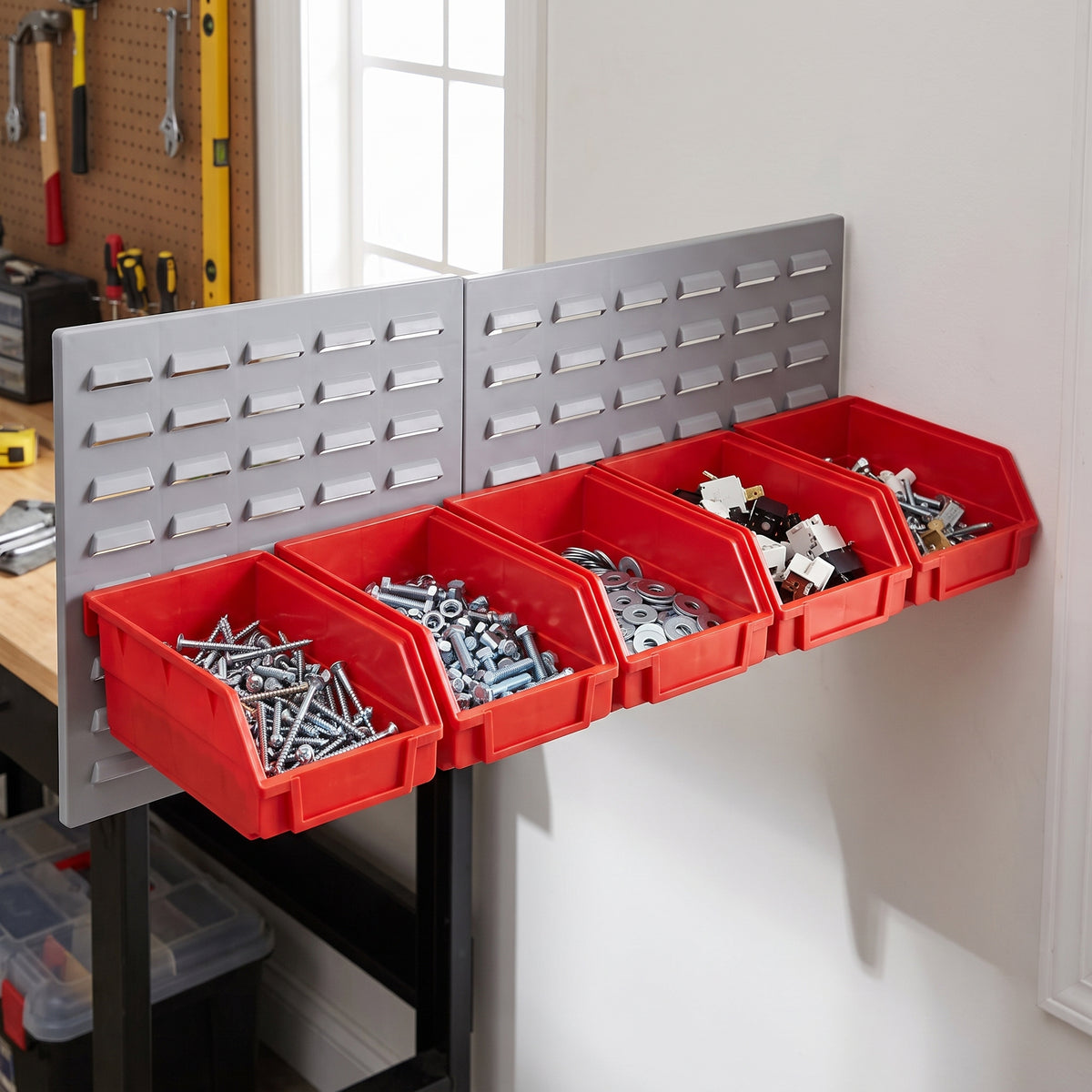 Row of large red hook-on bins on a louvre panel in a workshop